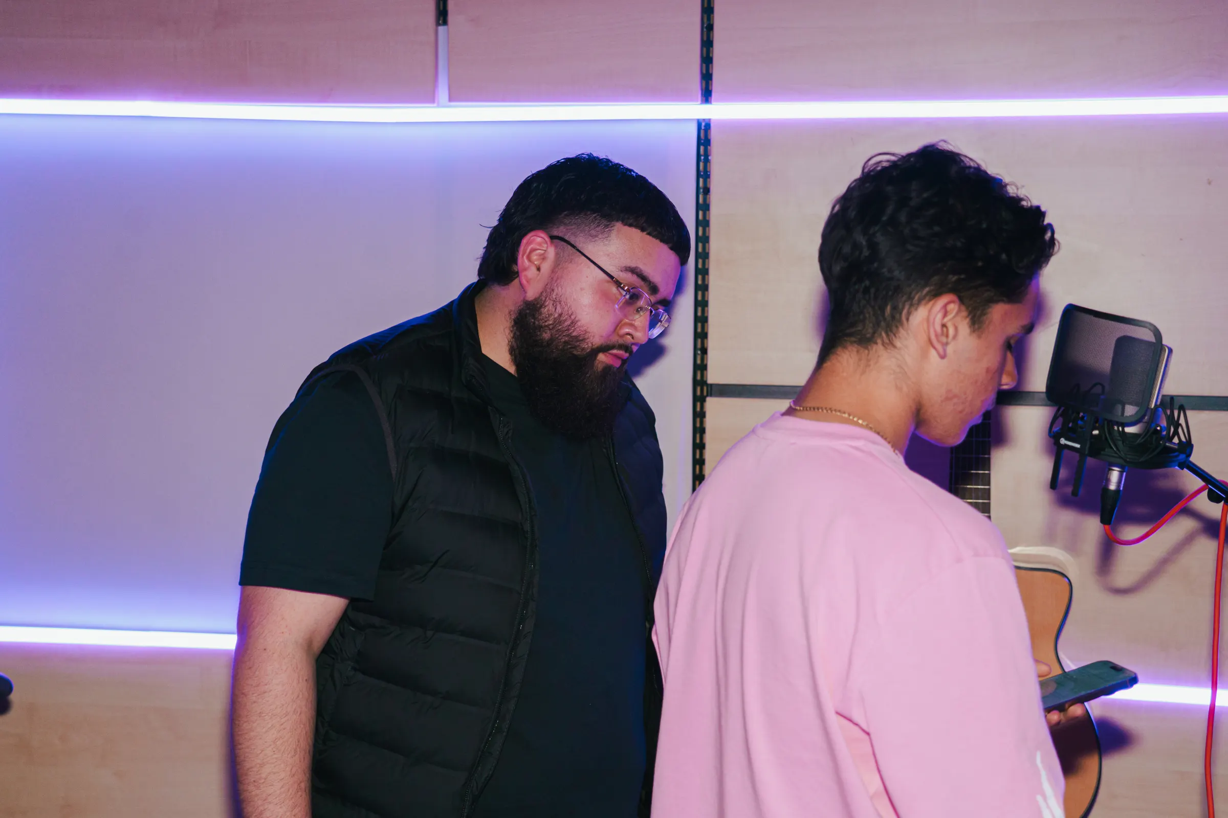 Een coach kijkt mee met een zanger in de studio