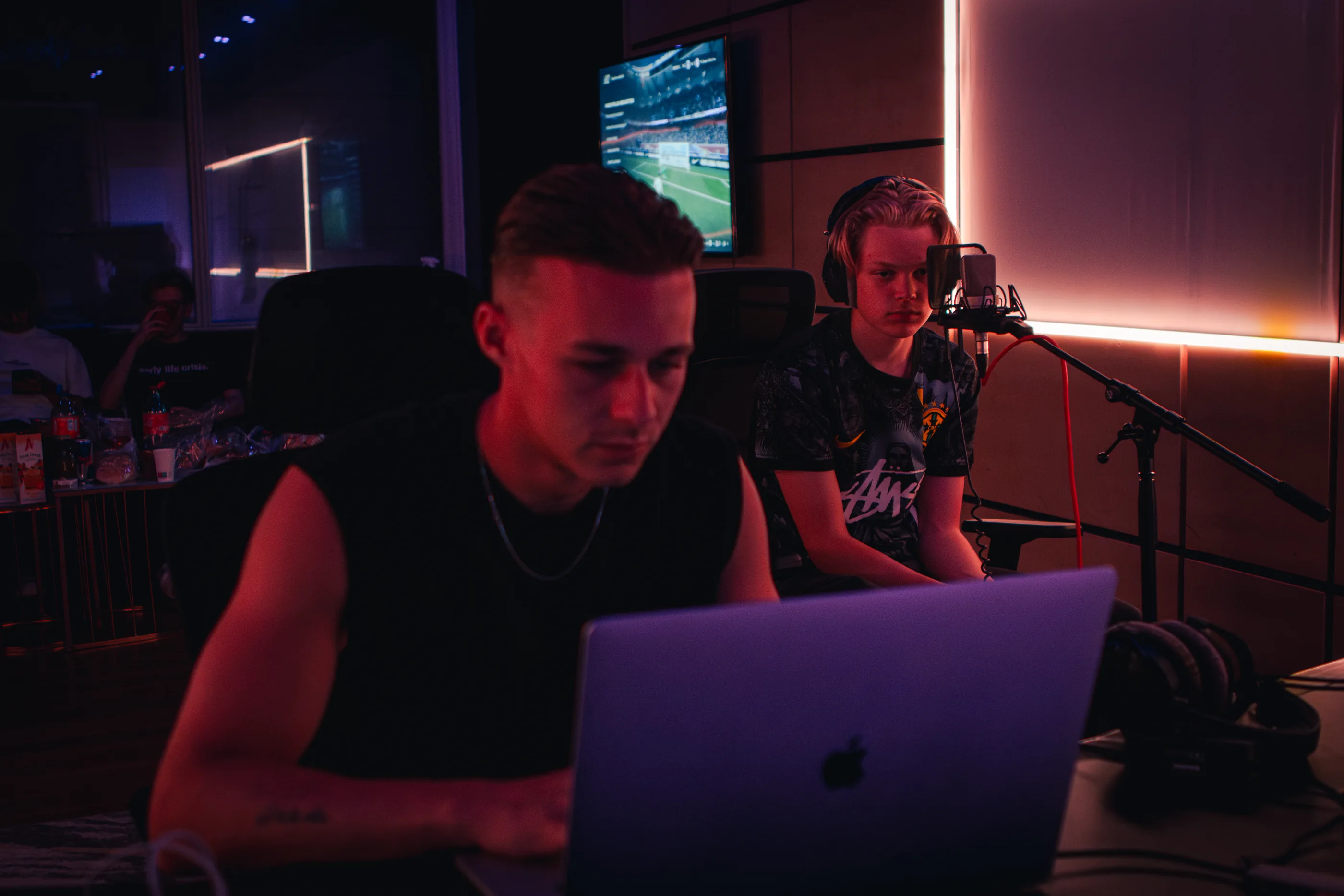 Twee makers achter een laptop in de studio, vocalist aan de microfoon