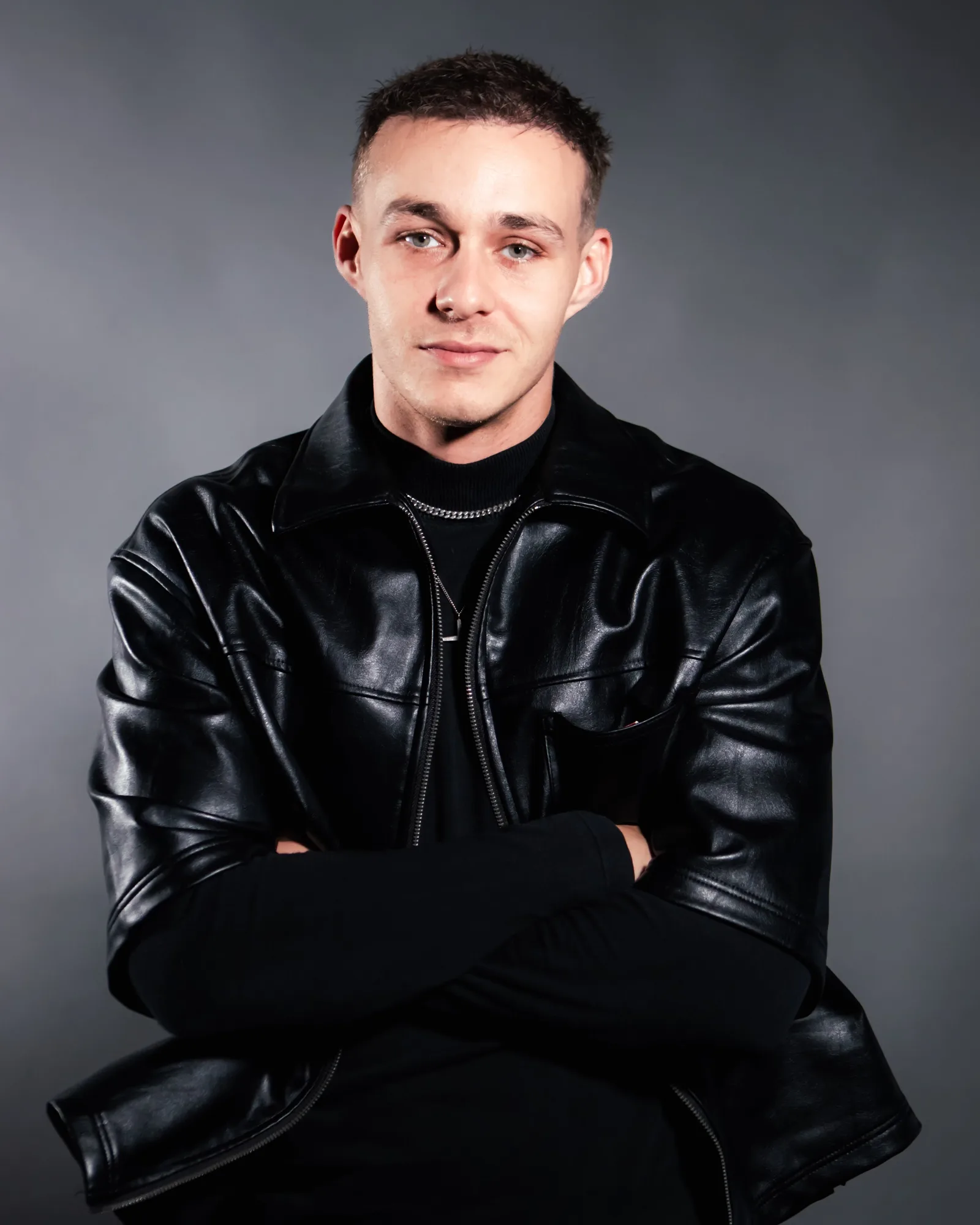 Portret in leren jas met gekruiste armen voor een grijze achtergrond