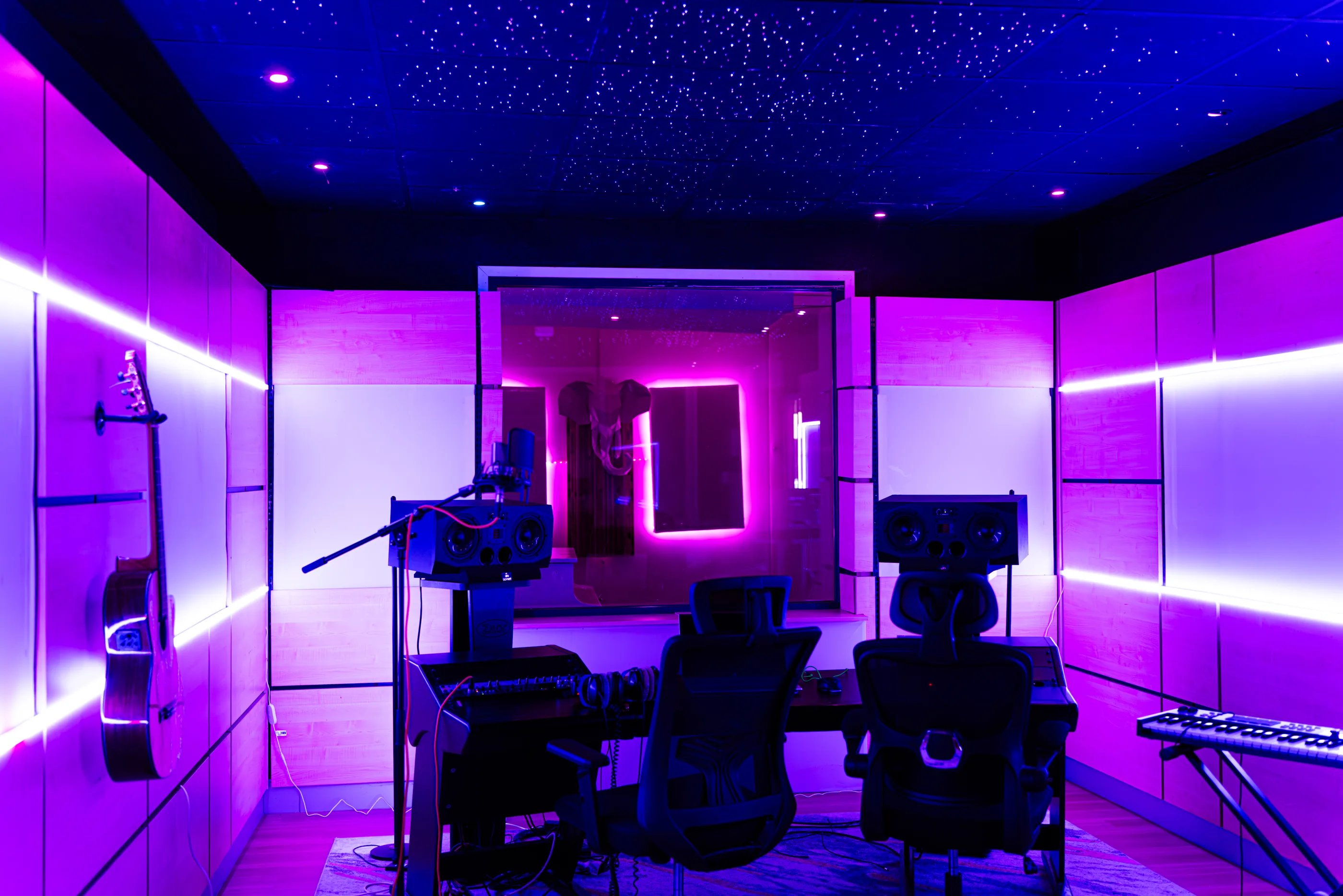 Studio 1 in paars licht met sterrenplafond, monitoren en gitaar